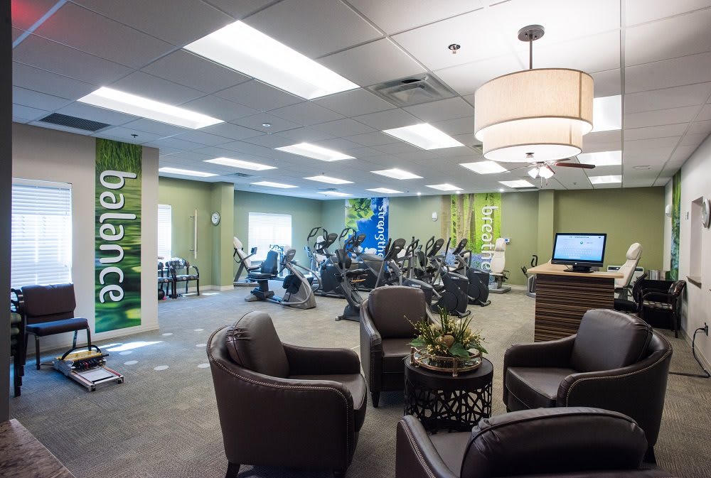 A modern fitness center with cardio machines and a comfortable seating area.