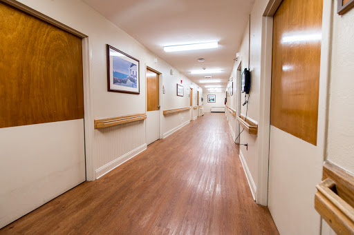 A well-lit hospital hallway with wooden doors and framed artwork.