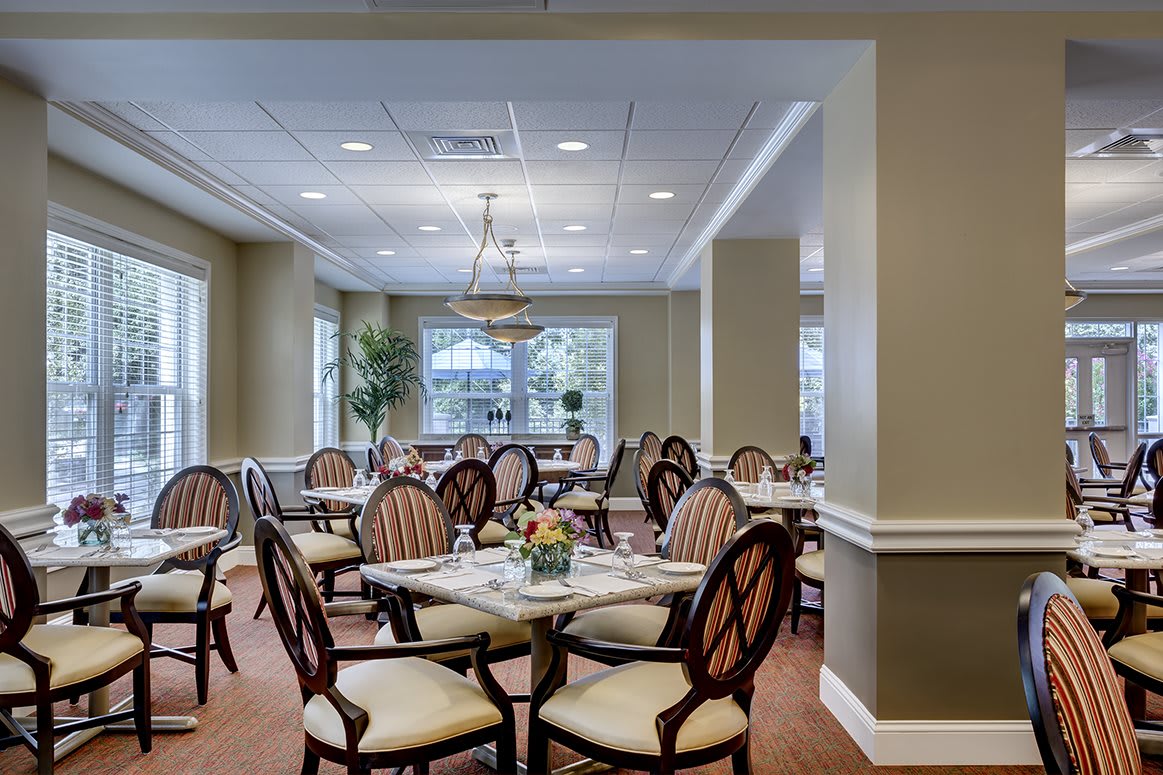 A well-lit dining room with elegantly arranged chairs and tables.
