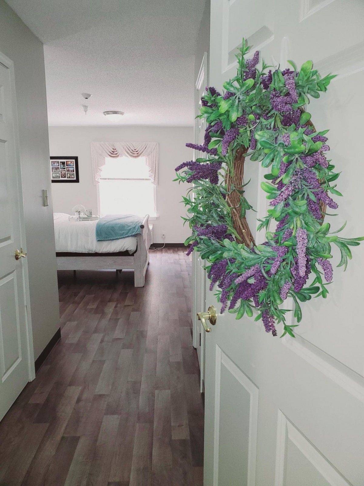 A cozy bedroom with a floral wreath hanging on the door.