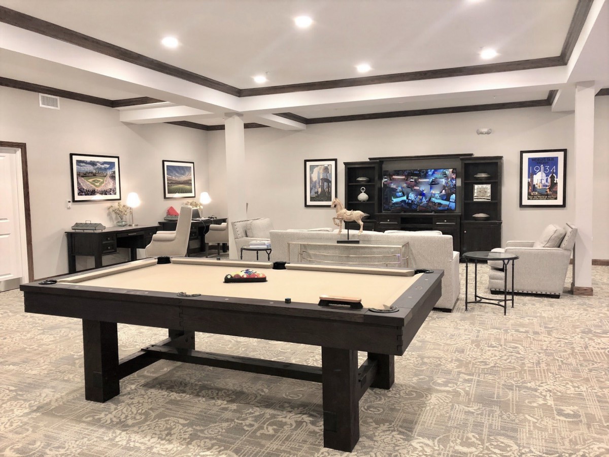 A modern game room featuring a pool table and comfortable seating area with a large television.