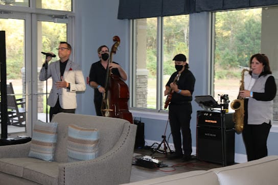 A band performing live indoors, featuring a guitarist, bassist, and vocalist.