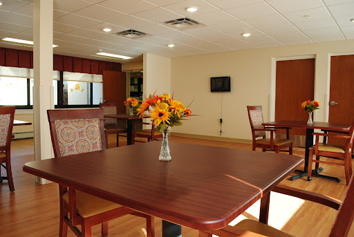 A cozy dining area featuring a wooden table with flowers and comfortable seating.