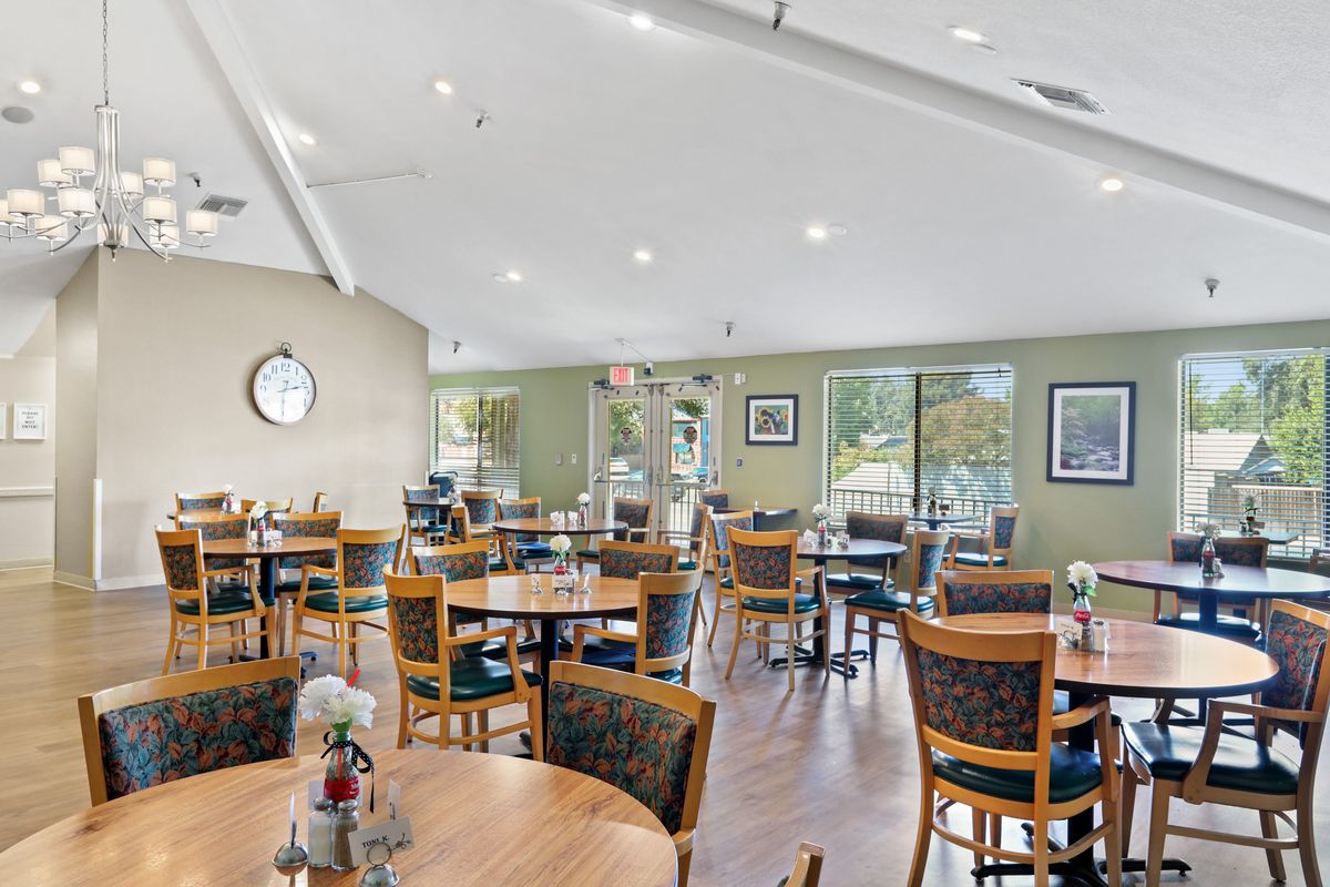 An indoor dining area with neatly arranged tables and chairs, decorated with flowers.
