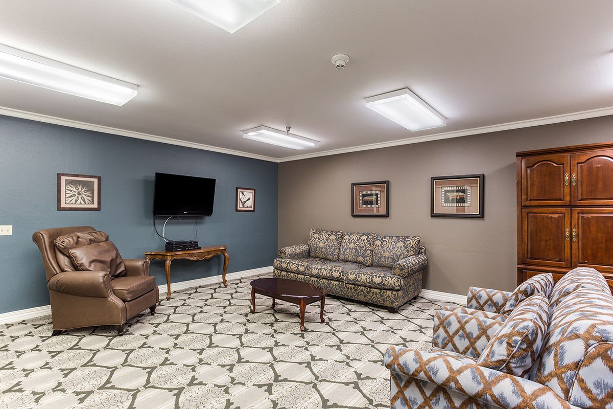 A cozy living room with a sofa, chairs, coffee table, and a TV on the wall.