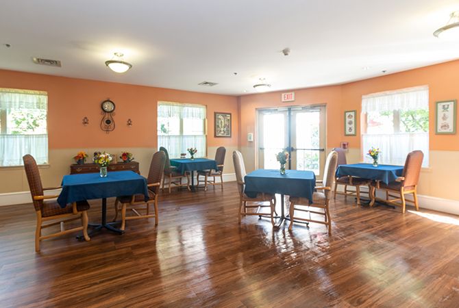 A well-lit dining room with blue tablecloths and wood flooring.
