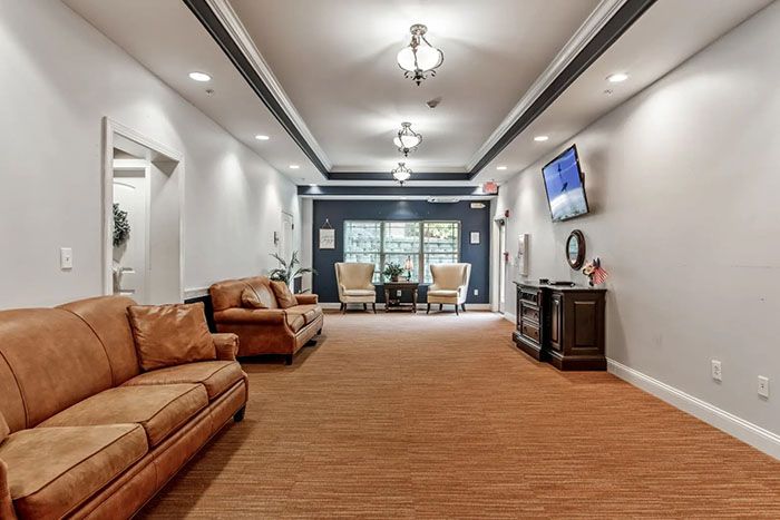 A well-lit lobby area featuring comfortable sofas, decor, and a wall-mounted television.