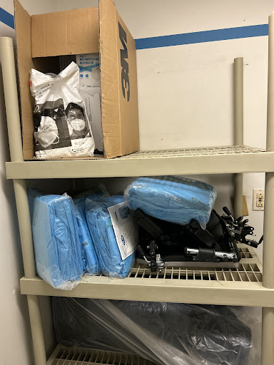 A storage shelf with various items including blue cleaning bags and a box.