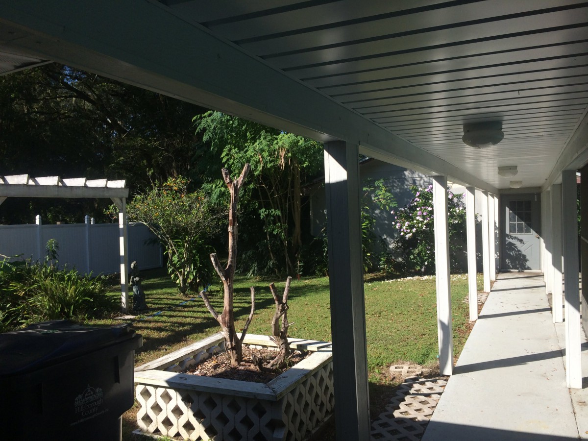 A sunny patio with a covered walkway and a garden area.