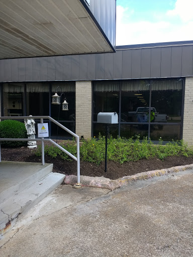 A view of the entrance to a building featuring landscaped areas and a mailbox.