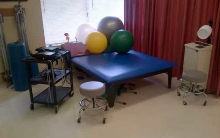 A physical therapy room featuring a large treatment table and exercise balls.