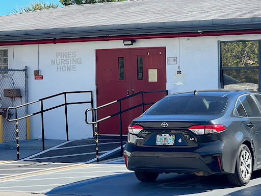 A view of a building entrance with a wheelchair ramp and a parked car.