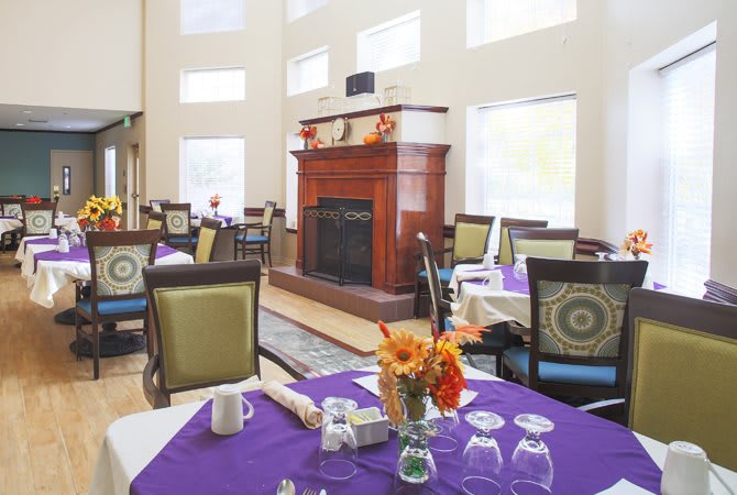 A cozy dining area with elegantly set tables and a fireplace.