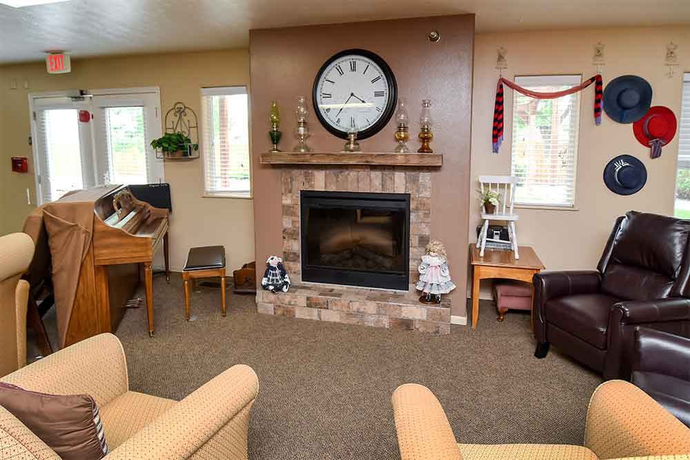 A cozy living room featuring a central fireplace with a large clock above it, surrounded by comfortable seating and home decor accents.
