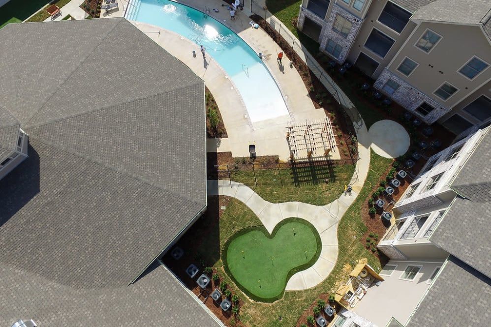 Aerial view of a landscaped outdoor area with a swimming pool and surrounding buildings.