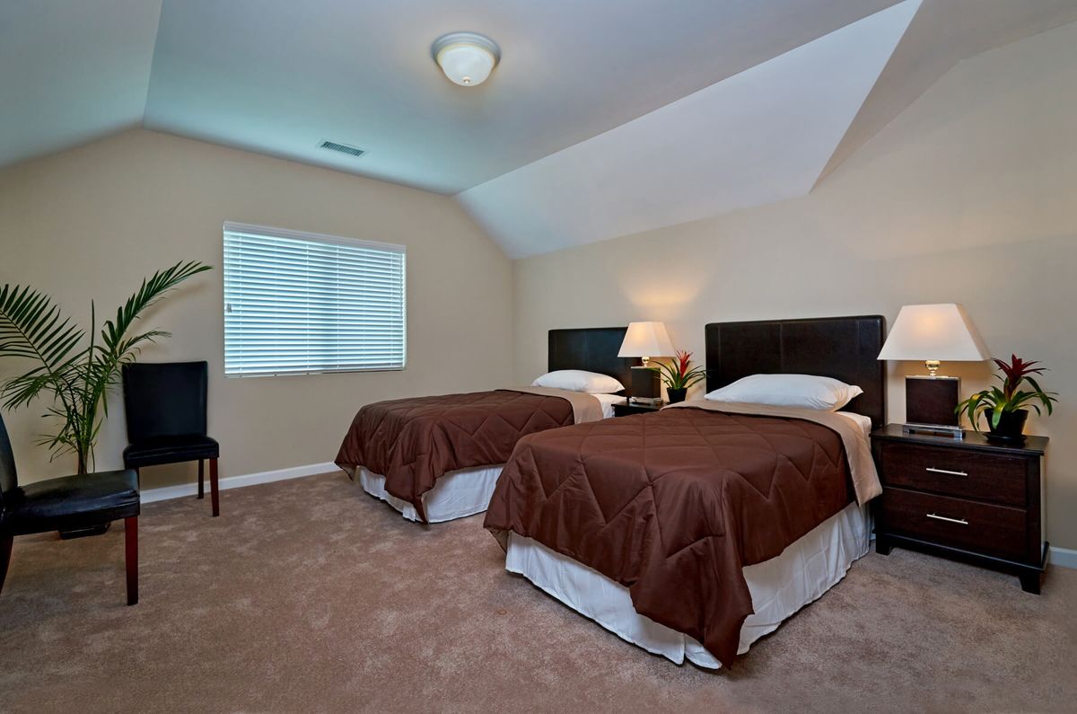 A cozy bedroom with twin beds, a nightstand, and soft lighting.