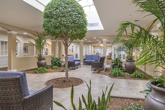A modern lobby with an indoor garden, featuring lush greenery and comfortable seating under natural light.