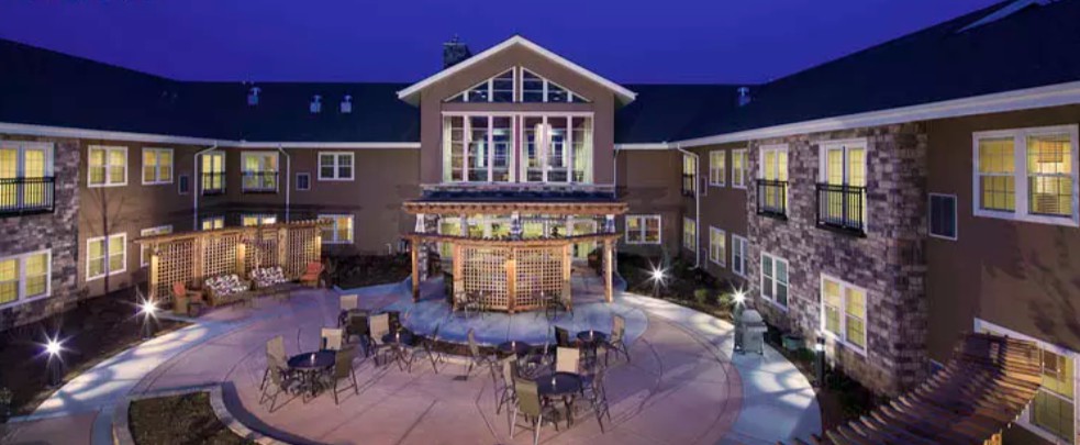 A nighttime view of a building with an illuminated outdoor seating area and patio.