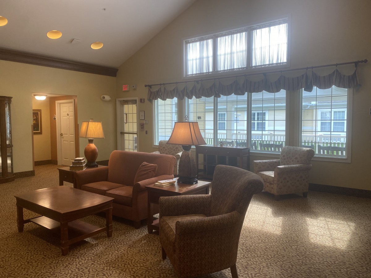 A cozy living room with comfortable seating, warm lighting from lamps, and large windows letting in natural light.