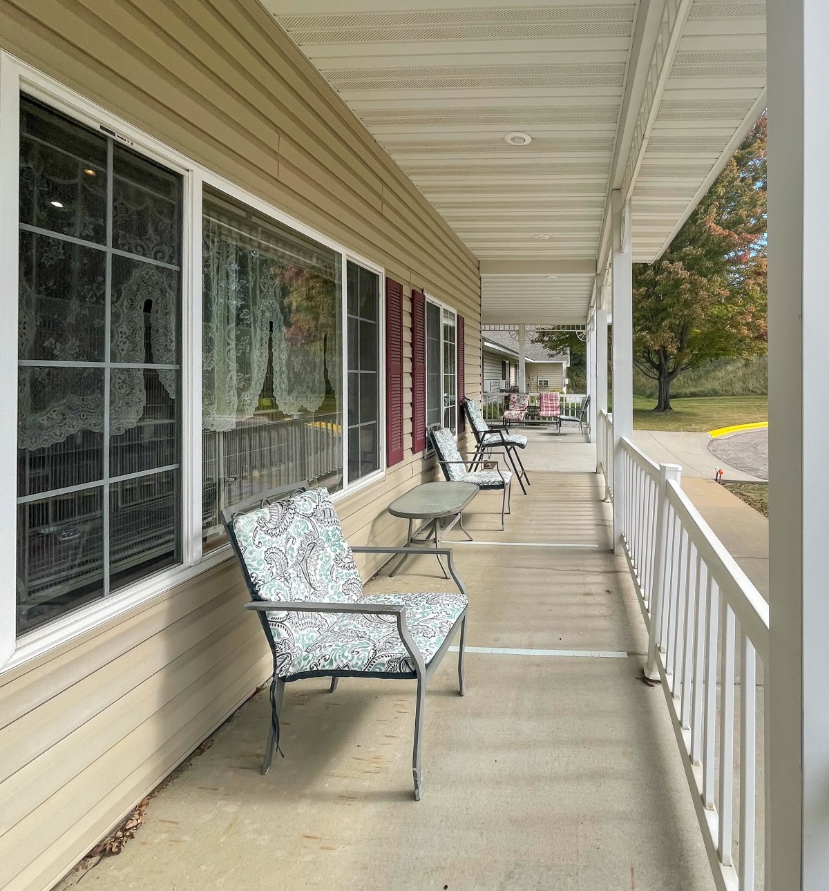 A cozy porch with cushioned chairs and a view of the neighborhood street.
