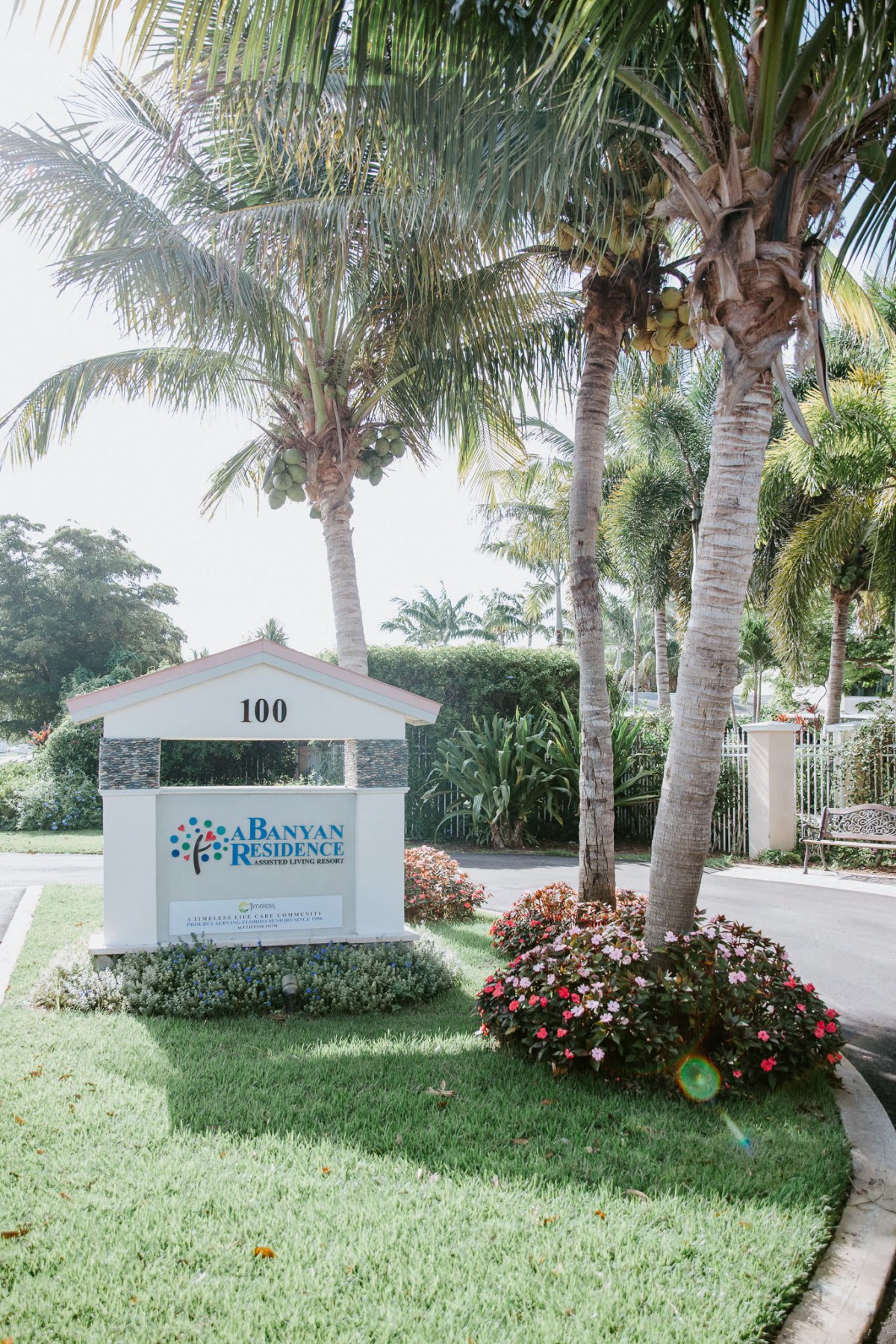 Entrance sign surrounded by palm trees and landscaping.