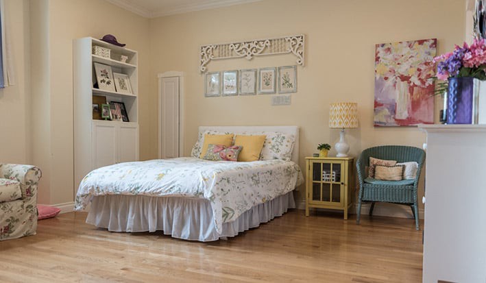A cozy bedroom with a neatly made bed, bookshelves, and tasteful decor.