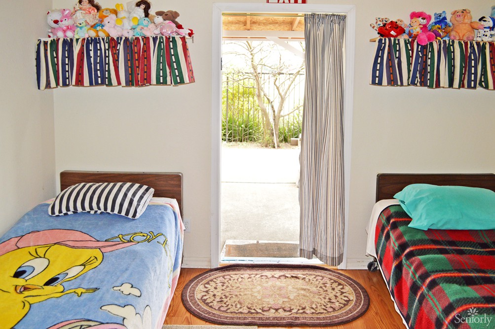 A cozy children's bedroom with twin beds and an open door letting in natural light.