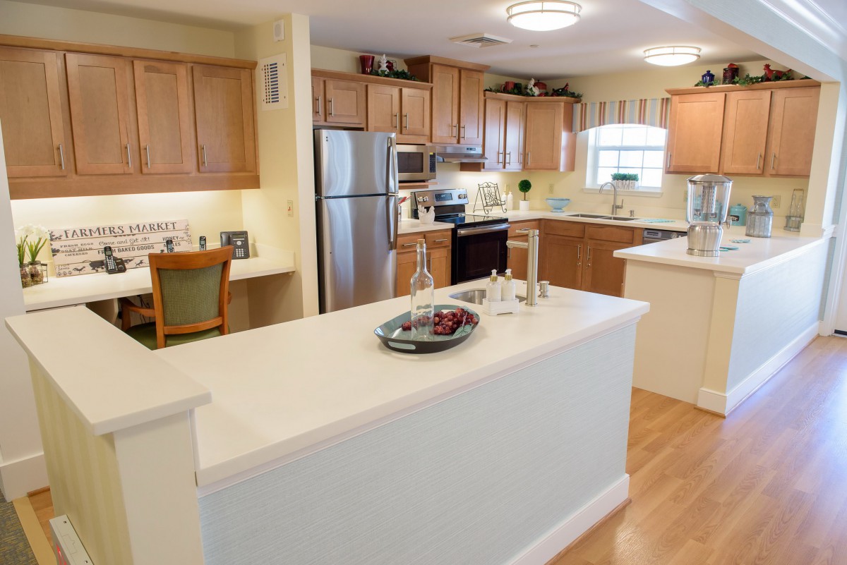 A modern kitchen with wooden cabinets, stainless steel appliances, and a spacious countertop.
