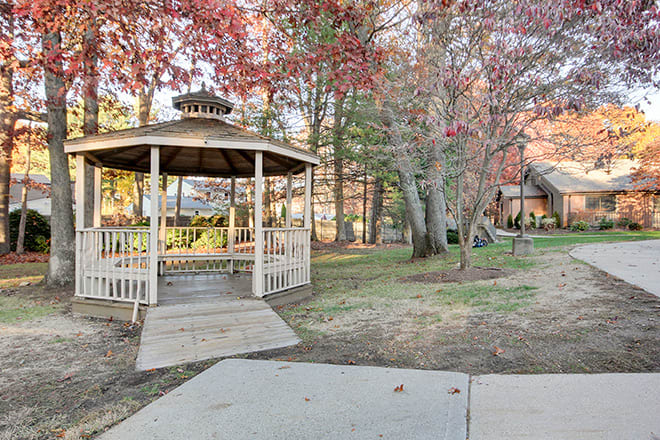 A peaceful park featuring a wooden gazebo surrounded by autumn foliage.