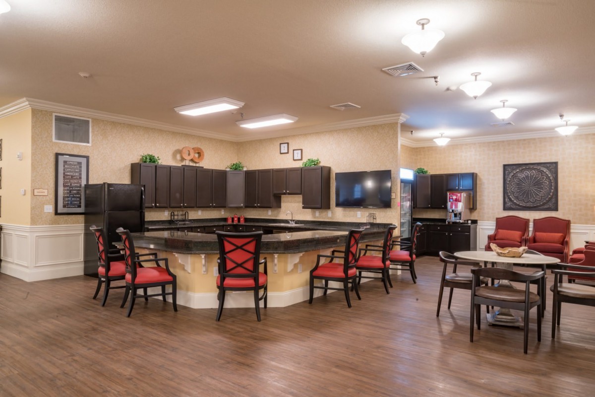 A modern kitchen and dining area featuring a large countertop with barstools and ample lighting.