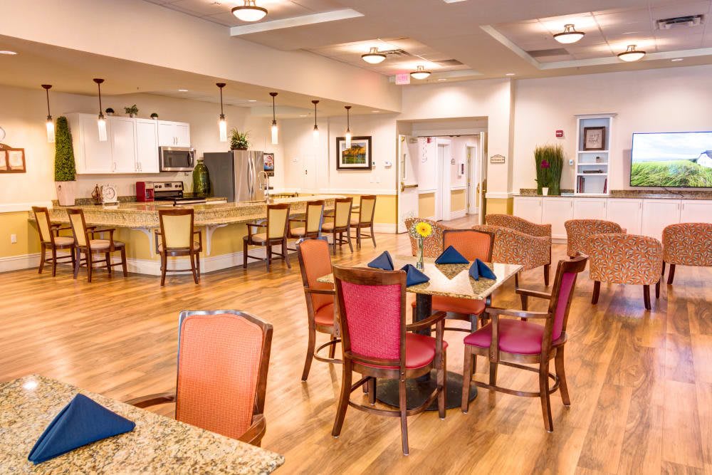 A modern dining area with a kitchen, open seating, and wooden flooring.