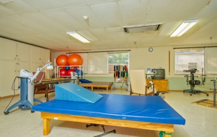 A physical therapy room equipped with gym mats, medicine balls, and exercise equipment.