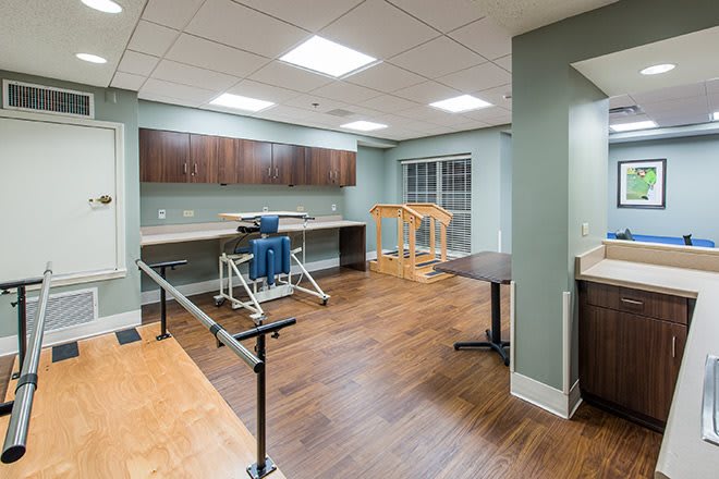 A well-equipped physical therapy room with exercise equipment and parallel bars.