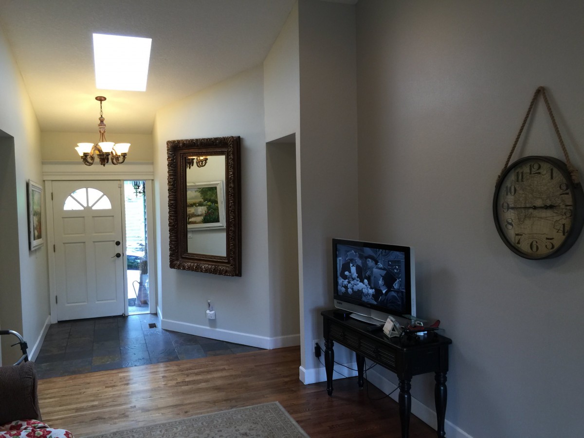 A cozy living space featuring a hallway with a large mirror, a small table with a television, and wood flooring.