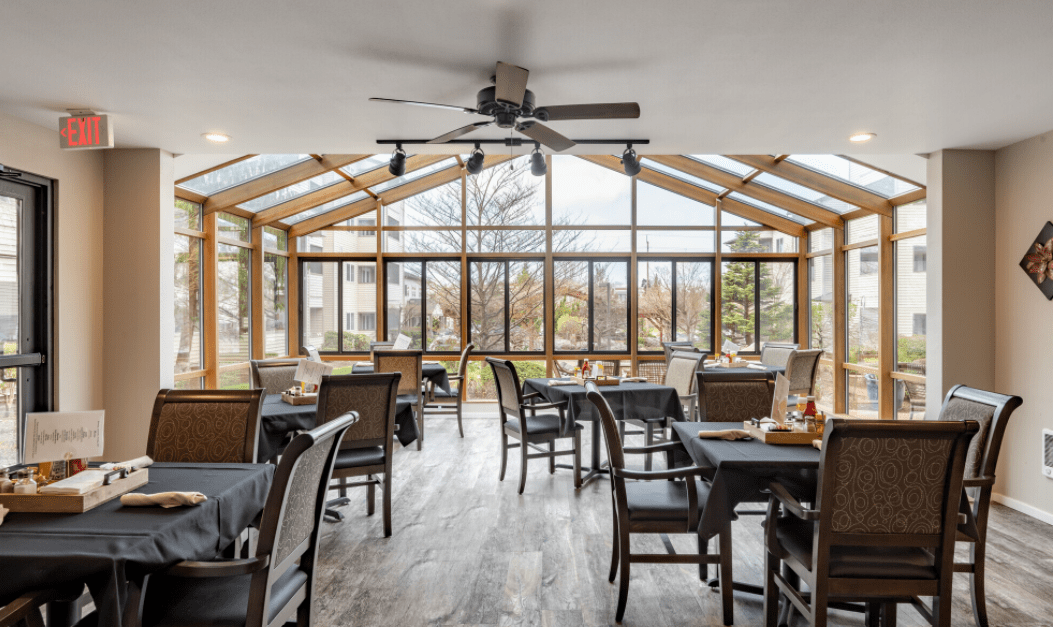 A cozy restaurant dining area with large windows and a ceiling fan.