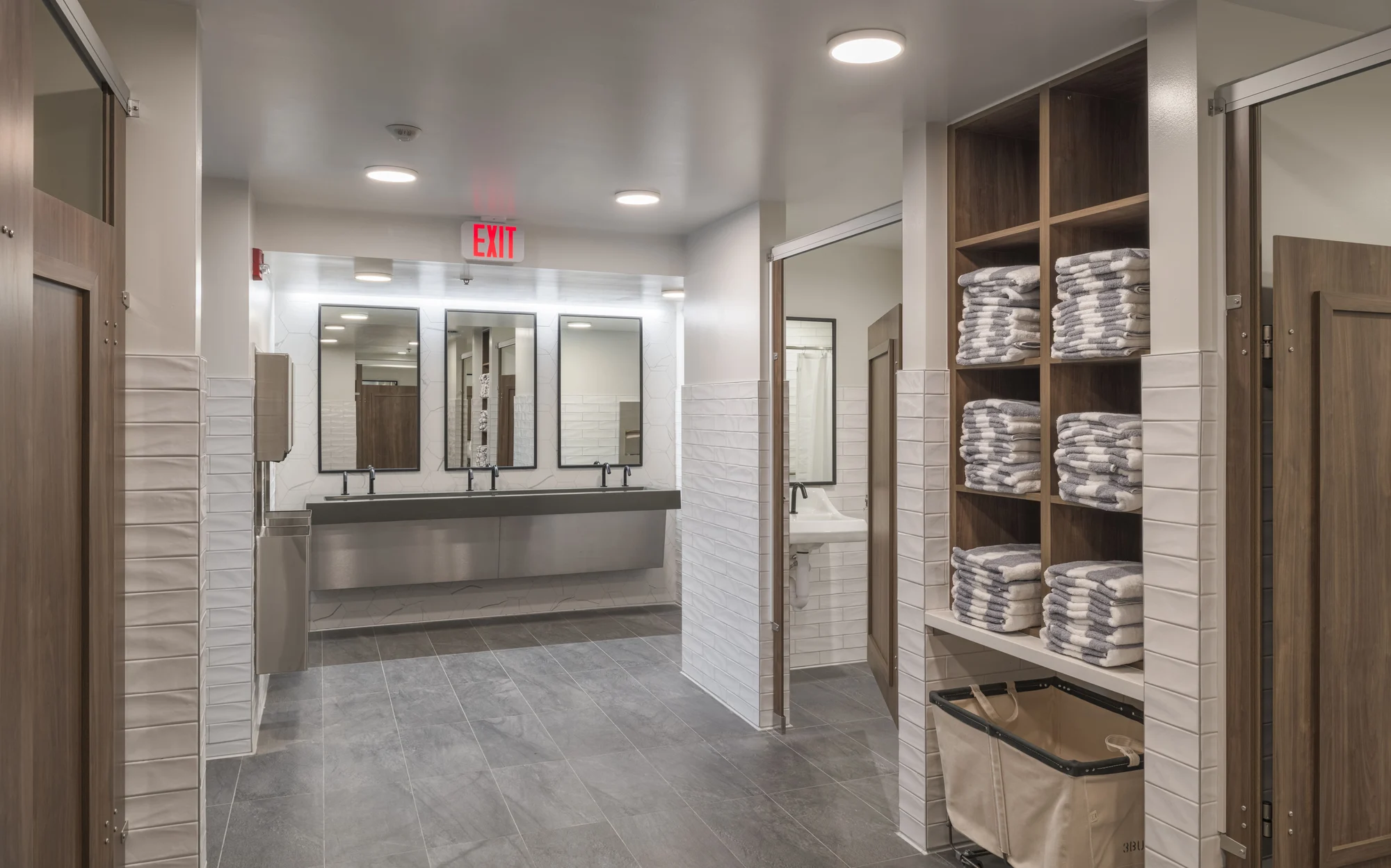 A clean and organized public bathroom with sinks, mirrors, and neatly stacked towels.