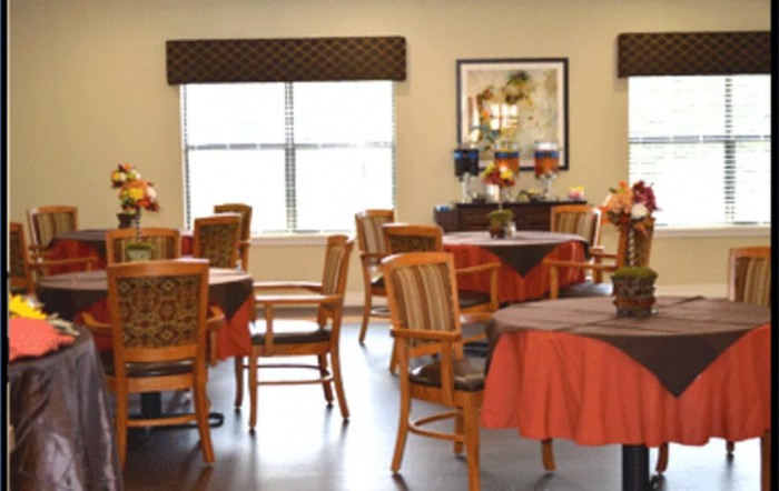 A neatly arranged dining area with tables and chairs, featuring warm decor.