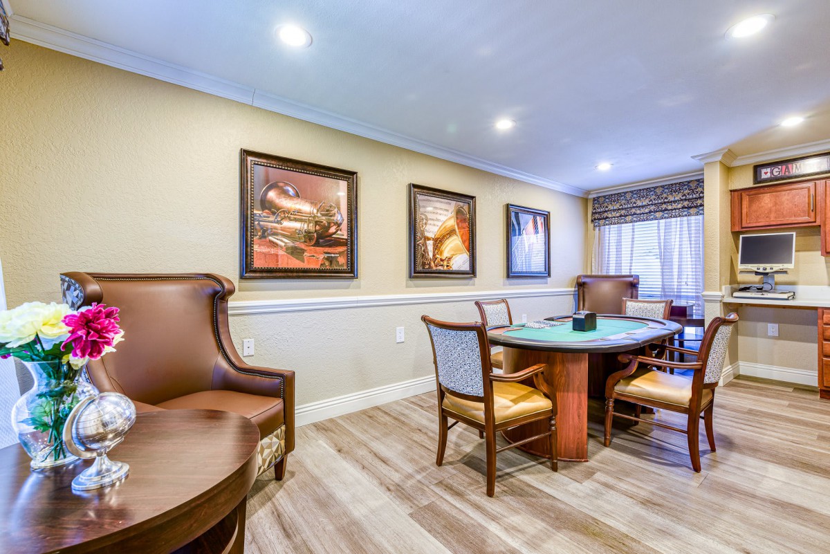 A cozy dining room with a round table, comfortable chairs, and artwork on the walls.