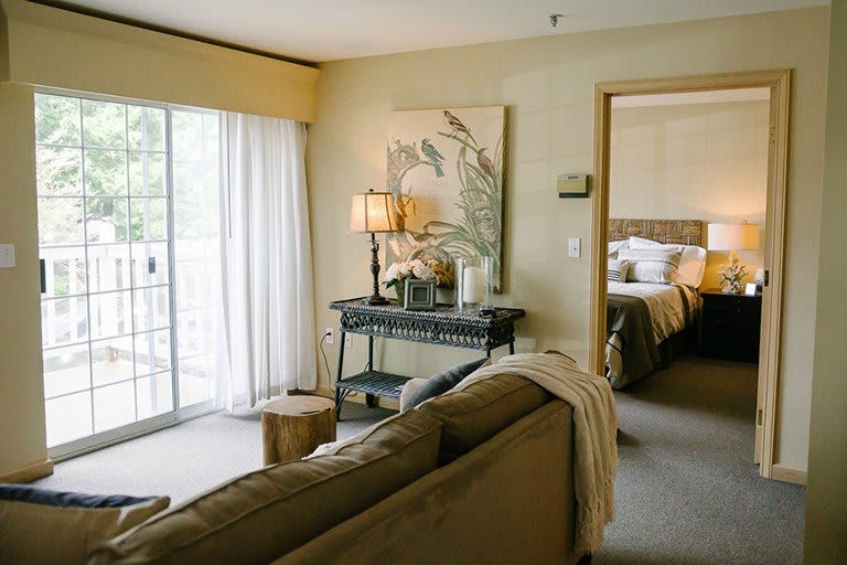 A cozy living room with a view into the bedroom, featuring stylish decor and ample natural light.