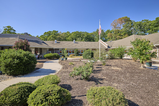 A serene view of a residential building surrounded by well-maintained landscaping and a flagpole.
