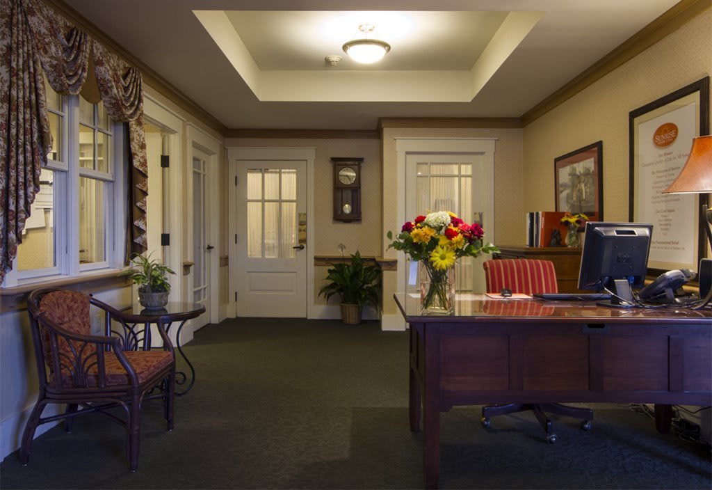 A cozy office interior featuring a desk adorned with colorful flowers and comfortable seating.
