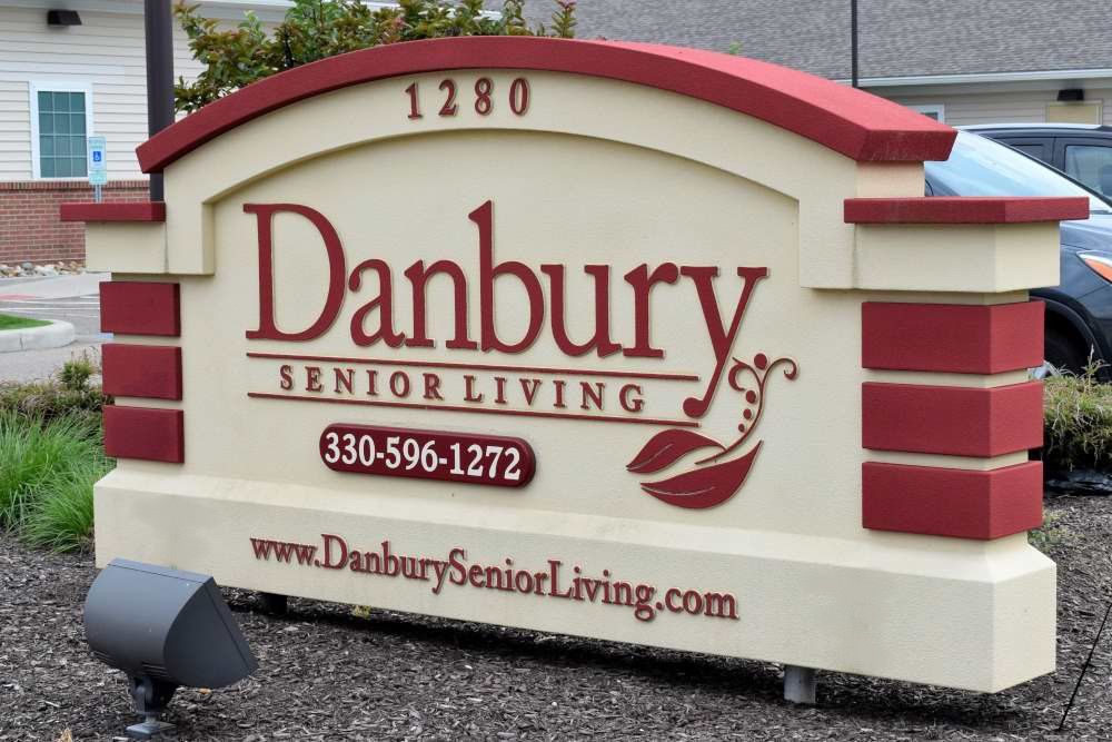 A sign for Danbury Senior Living featuring contact details and website information.