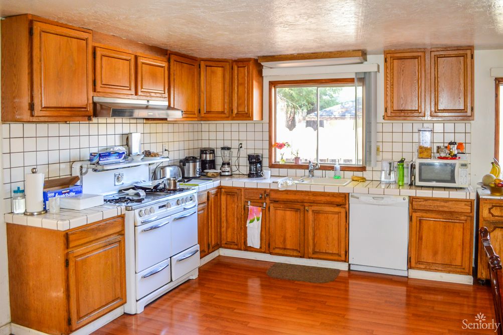 A cozy kitchen featuring wooden cabinets, modern appliances, and a large window over the sink.