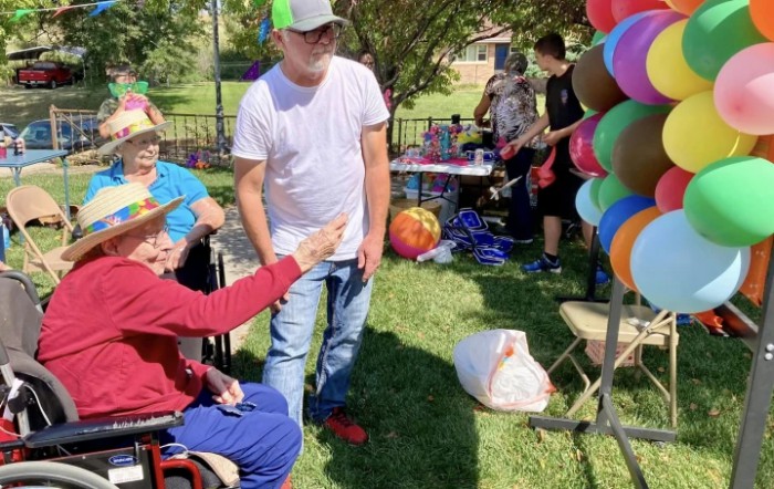 A group of people enjoys a sunny day at an outdoor event with colorful balloons.