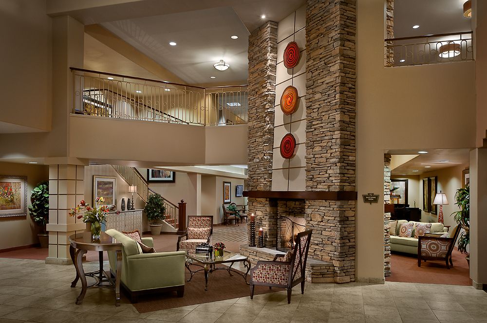 A modern and cozy lobby interior featuring a central fireplace and elegant seating arrangements.
