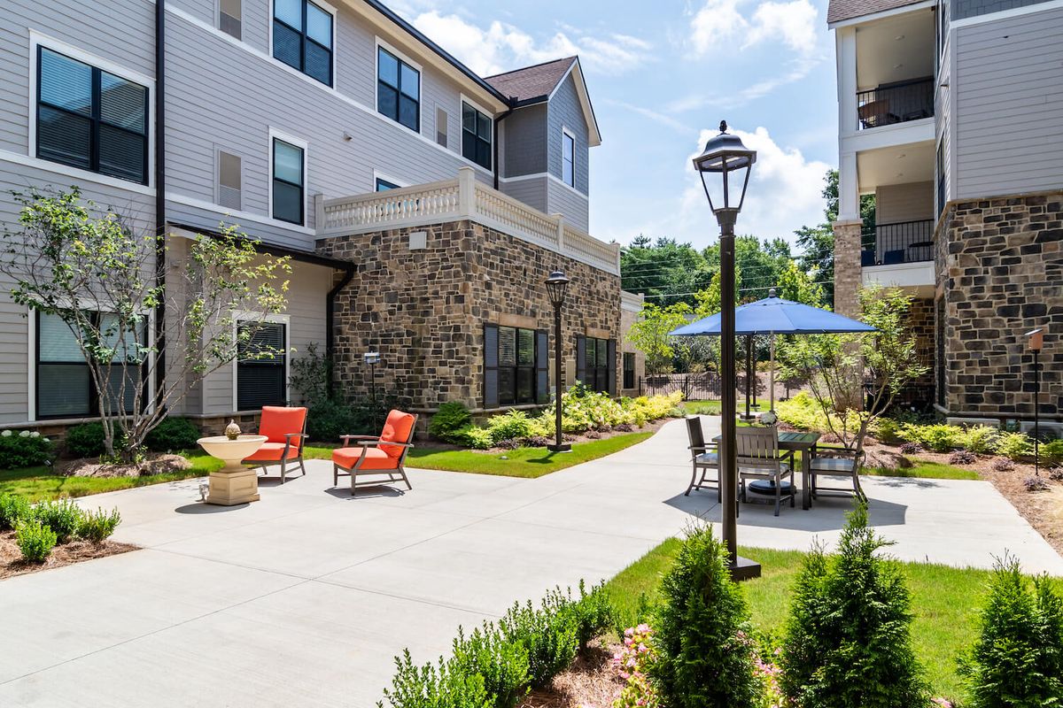 A well-maintained outdoor patio area with seating and an umbrella in a residential apartment complex.