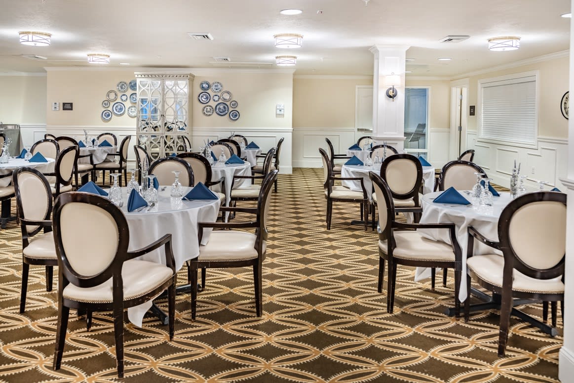 A well-furnished dining room with neatly arranged tables and chairs, featuring elegant decor.