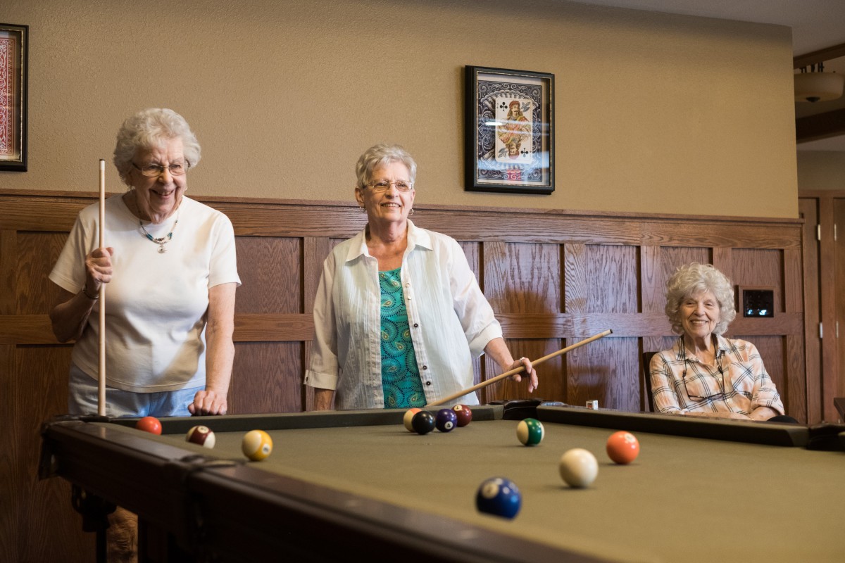 A group of senior women enjoying a game of billiards together.