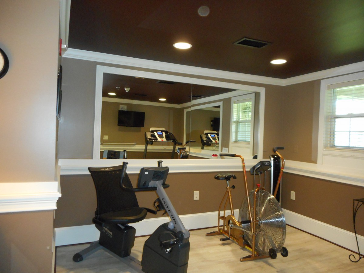 A home gym equipped with a stationary bike and treadmill, featuring large mirrors for workout convenience.