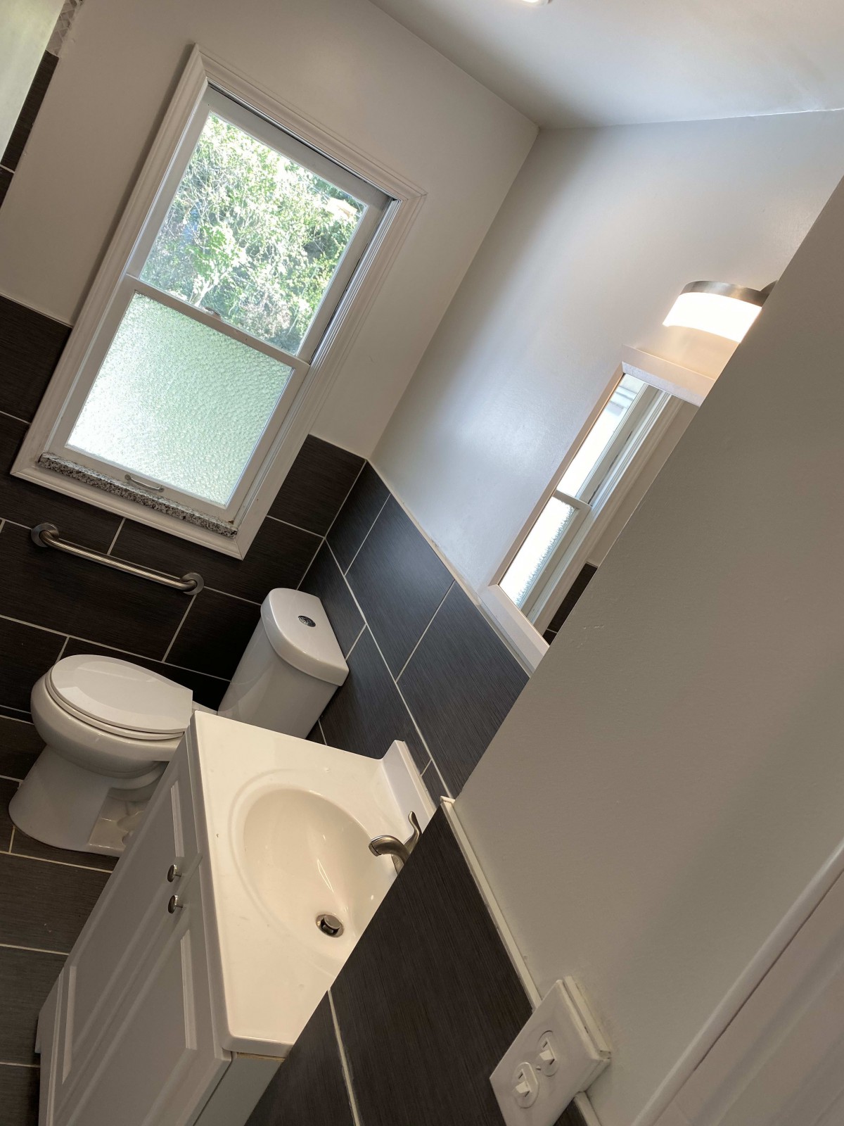 A modern bathroom with tiled walls and a view of the outdoors.